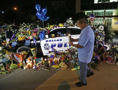 Alejandro Rodriguez places a candle Friday, July 8, 2016, in front of police cars decorated as a public memorial outside Dallas police headquarters, in memory of police who were shot Thursday in the city. (AP Photo/Gerald Herbert)