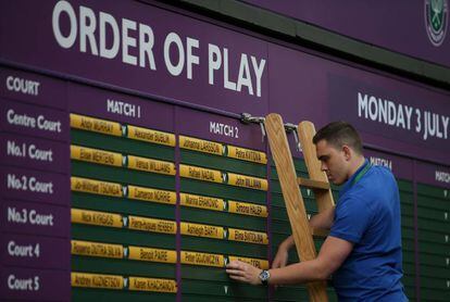 Un trabajador coloca los carteles con los nombres de los tenistas que participan en las primeras rondas del torneo de Wimblendon.