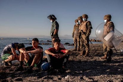 Soldados españoles custodian a un grupo de inmigrantes tras cruzar a Ceuta en la playa del tarajal, en mayo.