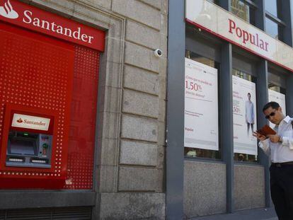 Un hombre espera junto a un cajero automático de Banco Santander.