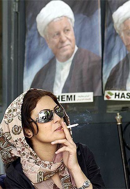 Una mujer fuma ante un cartel electoral de Rafsanyani, durante la campaña para las presidenciales, en junio de 2005.