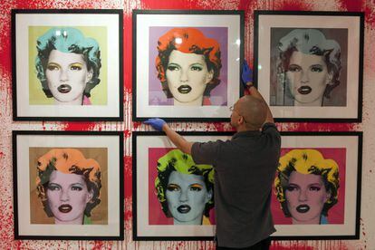 Un empleado coloca otras versiones del retrato de Kate Moss del célebre artista callejero.
