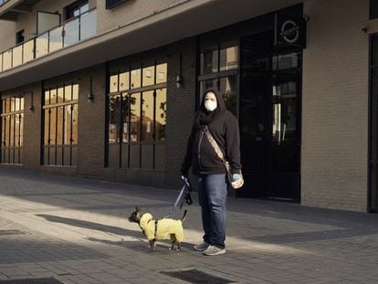 Una mujer pasea a su perro con un chubasquero.