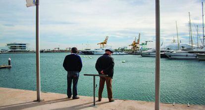 En la imagen dos hombres de espaldas hablan en el puerto de Valencia.