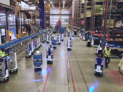 Robots y personas trabajan en un almacén industrial.