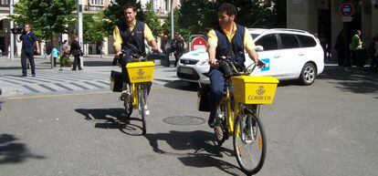Empleados de Correos llevan a cabo el reparto en bicicleta.  