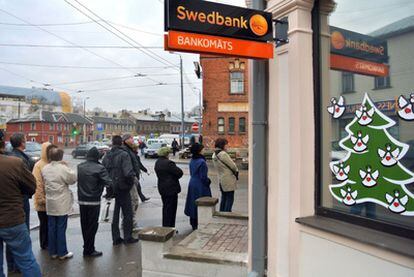Un grupo de personas hace cola ante un cajero del banco sueco Swedbank.