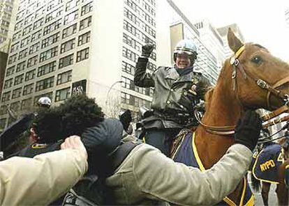 Un policía montado golpea a un manifestante mientras otro le sujeta, cerca de la ONU en Nueva York.