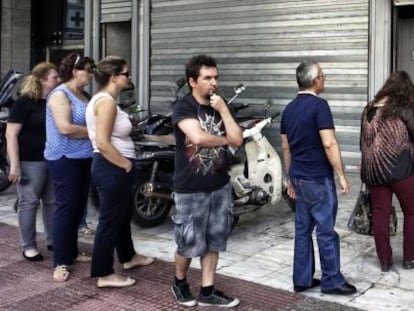 Un grupo de personas hace cola ante un cajero autom&aacute;tico de un banco griego, en Atenas, tras la imposici&oacute;n de un corralito por parte del Gobierno.