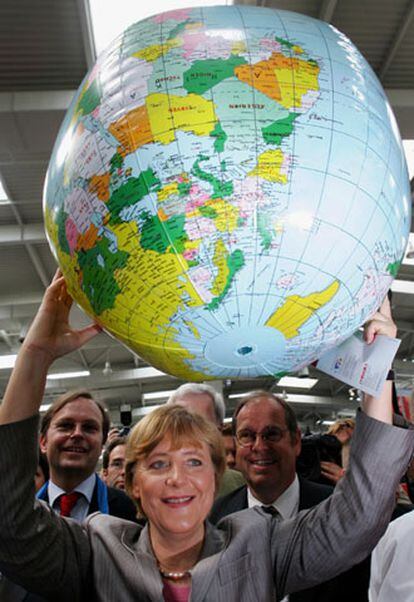 Merkel levanta un globo terráqueo, ayer en una visita a Hanover.