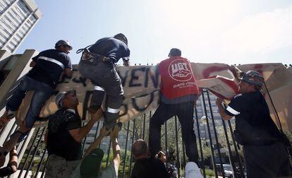 Un grupo de mineros participantes en la manifestación, colocan una pancarta en la verja del Ministerio de Industria