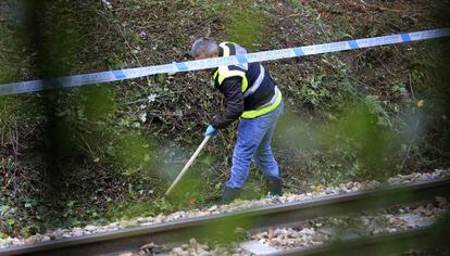 Un polic&iacute;a busca pruebas en las inmediaciones del apeadero ferroviario de La Arga&ntilde;osa, a las afueras de Oviedo.