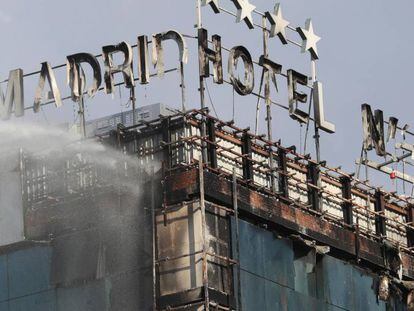 Bomberos extinguen las llamas tras un aparatoso incendio en la fachada exterior del Hotel Nuevo Madrid.