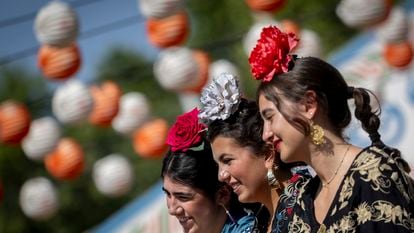 Tres chicas vestidas de flamenca con flores cabeza.