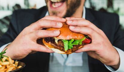Un hombre come en una hamburguesería. Algunas multinacionales han aprovechado la pandemia para aumentar sus ganancias vendiendo productos poco saludables.