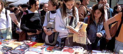 Varios visitantes en uno de los puestos de las librer&iacute;as por Sant Jordi, en 2017 en Barcelona.
