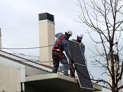 Dos técnicos instalan paneles solares en Madrid.