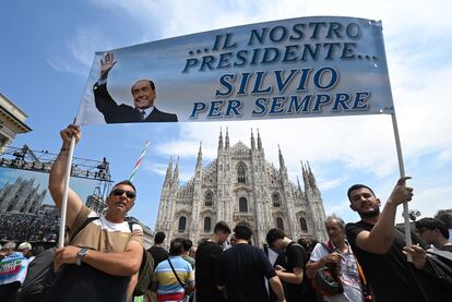Two people hold a banner with the slogan 'Our President, Silvio forever' in front of the Duomo in Milan.