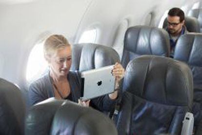 Una mujer utiliza un iPad dentro de un avi&oacute;n.