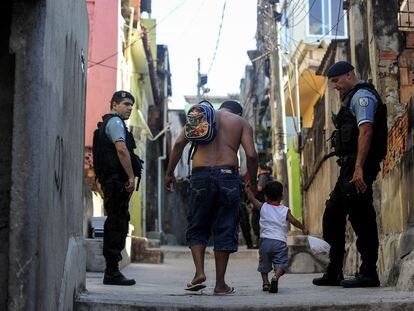 Dos policías observan a un hombre y su hijo durante un operativo en una favela de Río de Janeiro, en octubre de 2022.