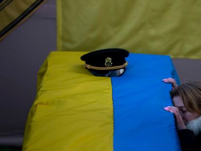 FILE - Svitlana Havryliuk kneels next to the coffin of her husband, Serhii, 48, at his funeral in Tarasivka village, near Kyiv, Ukraine, on Feb. 15, 2023. Havryliuk, an officer of the Azov Assault Brigade, died while defending the Azovstal steel plant in Mariupol on April 12, 2022. He was finally buried after DNA tests confirmed his identity. (AP Photo/Emilio Morenatti, File)