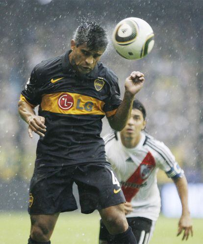 El defensa del Boca Ibarra cabecea el balón bajo la intensa lluvia.