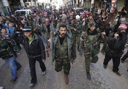 Rebeldes armados sirios marchan por una calle de Idlib. 