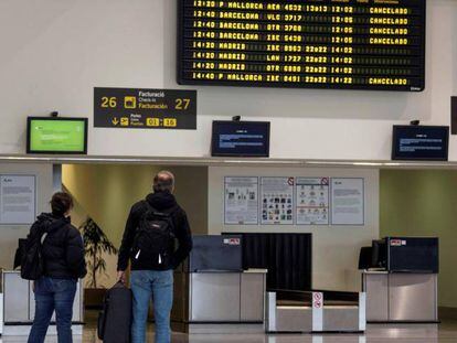 Dos pasajeros comprueban sus vuelos en el aeropuerto vacío de Menorca, en Mahón, este jueves.