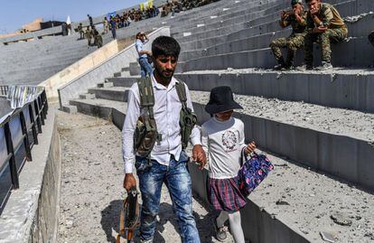 Un combatiente sirio camina con su hija en el estadio de Raqa este viernes durante las celebraciones de la proclamación oficial de liberación de la ciudad.