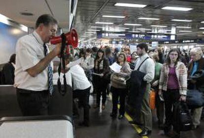 En la imagen, un trabajador de Aerolíneas Argentinas habla a través de un megáfono a los viajeros que se ven afectados por el retraso de los vuelos. EFE/Archivo