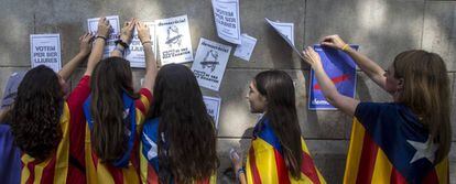 Varias estudiantes enganchan carteles en la pared de la Universidad de Barcelona