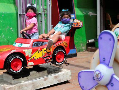 Dos niñas juegan en un coche llevando mascarilla, en Nicaragua.