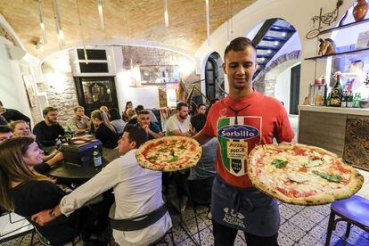 Un camarero sirve dos pizzas margarita en uno de los restaurantes Sorbillo en Nápoles.