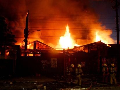 Los bomberos tratan de apagar el fuego en un almacén incendiado durante los disturbios en Chile.