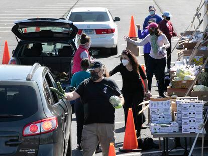 Voluntarios entregan alimentos a vehículos en un centro de distribución en Connecticut, EE. UU. (Foto AP / Mark Lennihan)