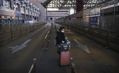 Una mujer en el estacionamiento para taxis vacío de una estación de tren en el oeste de Pekín.