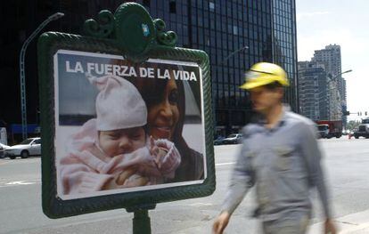 Un obrero camina frente a un cartel electoral.