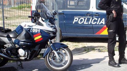 Un agente de la Policía Nacional, junto a dos vehículos policiales, en una imagen de archivo.