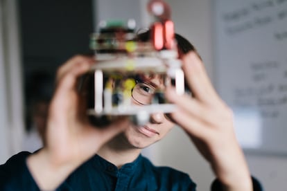 Un adolescente analiza un robot electrónico casero.