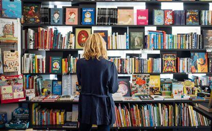Una mujer observa la estantería de una librería.