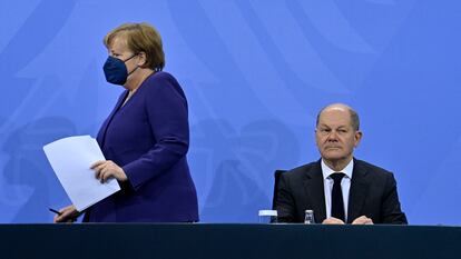 La canciller en funciones, Angela Merkel, llega a la rueda de prensa para anunciar las nuevas restricciones y se sienta junto a su sucesor, Olaf Scholz, este jueves en Berlín.