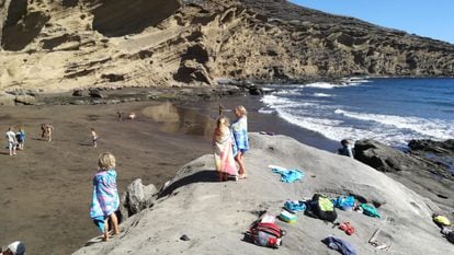 Varios niños juegan en la bajamar y observan las olas tras un baño en el mar.