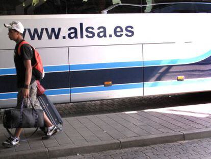 Un joven con maletas junto a un autobús de la empresa Alsa en la Estación Sur de Madrid.