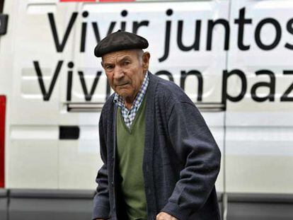 Un hombre camina por delante de un vehículo con un eslogan electoral, en Bilbao.