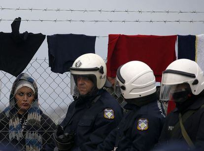 Una muijer mira a policías griegos en la frontera con Macedonia.