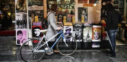 Una chica ojea discos de vinilo junto a su vieja bicicleta. 