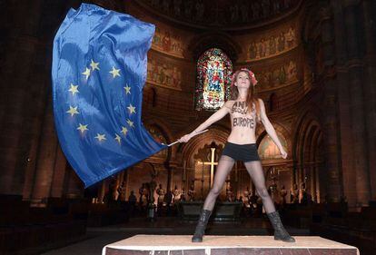 Una activista de Femen ondea una bandera de la UE en el interior de la catedral de Estrasburgo en protesta por la pr&oacute;xima visita del papa Francisco al parlamento Europeo.
