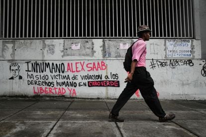 A man walks in front of a graffiti in support of Alex Saab on the streets of Caracas.