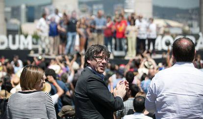 El presidente catalan, Carles Puigdemont (c), mira a la gente durante la lectura de un manifiesto independentista leído por Josep Guardiola (al fondo).