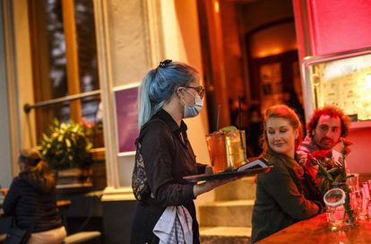 Stephanie Llynch sirve un cocktail a unos clientes cuando los bares de Berlín acaban de abrir de nuevo al público tras la crisis de Coronavirus.